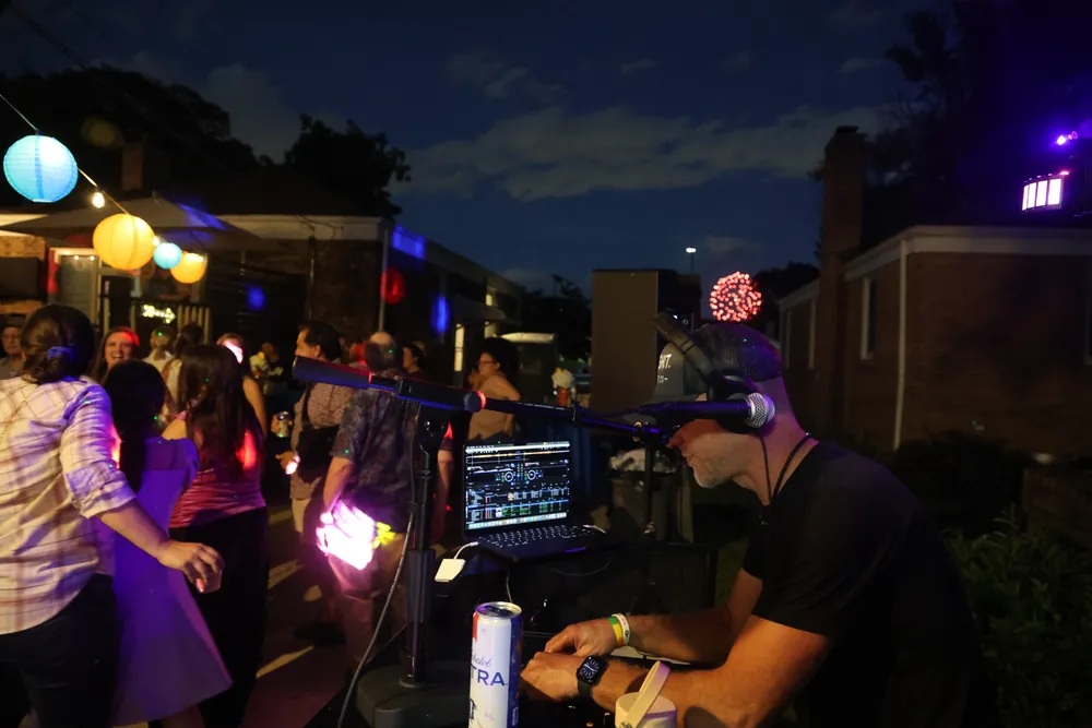 A packed outdoor dance floor at dusk under strings of lights
